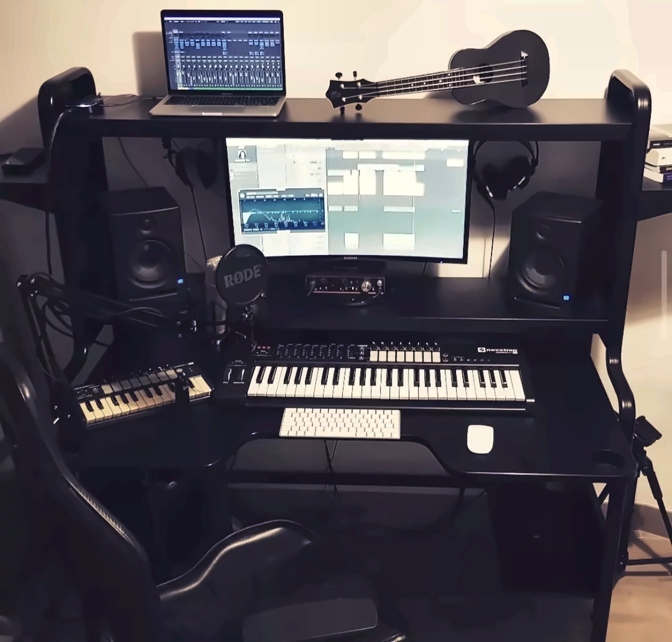 Stanowisko do produkcji muzycznej z mikrofonem, monitorami odsłuchowymi, klawiaturami MIDI i instrumentem strunowym